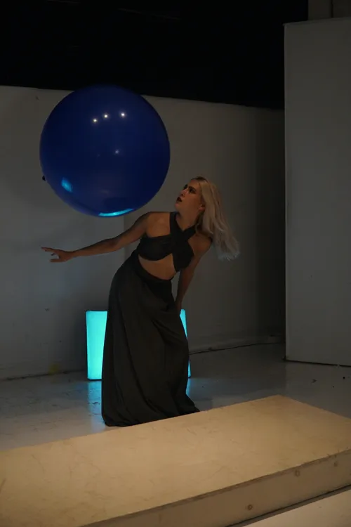 From This is Me Eating___: Luisa moving with a large blue ballon floating near her.